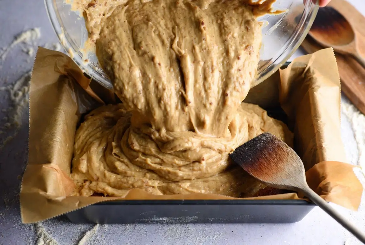 banana cake batter being poured into 9x13 baking pan
